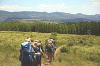 A group of hikers with heavy backpacks walking on a dirt road through the grasslands. Original public domain image from Wikimedia Commons