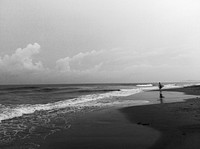 Black and white beach photography, man on a seashore. Original public domain image from Wikimedia Commons