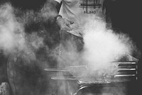 A person cooking food over a smokey barbeque in Vinaròs. Original public domain image from <a href="https://commons.wikimedia.org/wiki/File:Great_sunday!_(Unsplash).jpg" target="_blank" rel="noopener noreferrer nofollow">Wikimedia Commons</a>