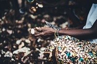 A woman wearing a patterned shirt, peeling food in Sierra Leone. Original public domain image from <a href="https://commons.wikimedia.org/wiki/File:Carving_Food_(Unsplash).jpg" target="_blank" rel="noopener noreferrer nofollow">Wikimedia Commons</a>