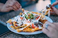 People sharing a plate of Mexican nachos with vegetables and meat. Original public domain image from <a href="https://commons.wikimedia.org/wiki/File:Eating_Nachos_(Unsplash).jpg" target="_blank" rel="noopener noreferrer nofollow">Wikimedia Commons</a>