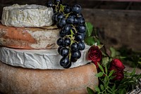 Stack of camembert, brie, and assorted gourmet cheeses with grapes and roses. Original public domain image from <a href="https://commons.wikimedia.org/wiki/File:Grapes_and_cheese_(Unsplash).jpg" target="_blank" rel="noopener noreferrer nofollow">Wikimedia Commons</a>