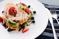 A plate of pancake with strawberries and kiwi toppings. Original public domain image from Wikimedia Commons