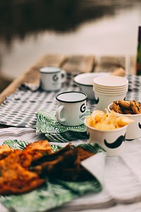 Picnic table with cups of chips, cookies, and grilled food. Original public domain image from <a href="https://commons.wikimedia.org/wiki/File:Picnic_(Unsplash).jpg" target="_blank" rel="noopener noreferrer nofollow">Wikimedia Commons</a>