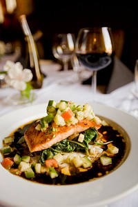 A deep dish with a meal with salmon and zucchini next to a wine glass on a white tablecloth. Original public domain image from <a href="https://commons.wikimedia.org/wiki/File:Meal_with_salmon_and_zucchini_(Unsplash).jpg" target="_blank" rel="noopener noreferrer nofollow">Wikimedia Commons</a>