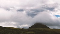 Two people hiking across grassy plain underneath cloudy sky. Original public domain image from Wikimedia Commons