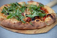 Freshly baked pizza topped with arugula for dinner. Original public domain image from Wikimedia Commons