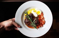 Hand holds a plate of steak, soft boiled egg, and tomatoes. Original public domain image from <a href="https://commons.wikimedia.org/wiki/File:Steak_Dinner_(Unsplash).jpg" target="_blank" rel="noopener noreferrer nofollow">Wikimedia Commons</a>
