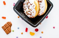 Donuts with white frosting and pistachio nuts on top, gummy bears, sweets, and a piece of a chocolate bar. Original public domain image from <a href="https://commons.wikimedia.org/wiki/File:Sweet_Tooth_(Unsplash).jpg" target="_blank" rel="noopener noreferrer nofollow">Wikimedia Commons</a>