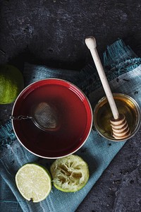 Tea steeping in a red mug with lemons and honey on a blue towel and black table. Original public domain image from Wikimedia Commons