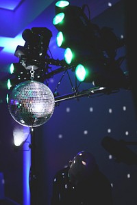 A bald man standing under a disco ball hanging from the spotlights. Original public domain image from Wikimedia Commons