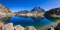 Jagged mountains reflected on the surface of a clear mountain lake. Original public domain image from <a href="https://commons.wikimedia.org/wiki/File:Mountains_reflected_in_a_lake_(Unsplash).jpg" target="_blank" rel="noopener noreferrer nofollow">Wikimedia Commons</a>