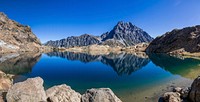 Jagged mountains reflected on the surface of a clear mountain lake. Original public domain image from Wikimedia Commons