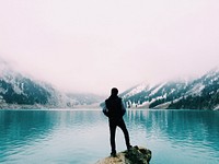 Man standing on cliff edge, glacier lake. Original public domain image from Wikimedia Commons