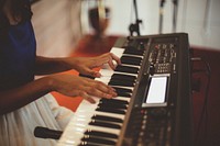 A woman playing the keyboard in a small room. Original public domain image from Wikimedia Commons