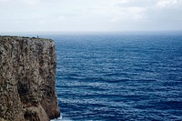 A rocky cliff overlooking a brilliant blue sea at Sagres. Original public domain image from Wikimedia Commons