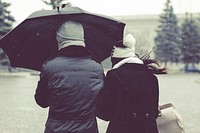 A couple in knit caps share an umbrella in the snow in the winter. Original public domain image from <a href="https://commons.wikimedia.org/wiki/File:Couple_sharing_umbrella_(Unsplash).jpg" target="_blank" rel="noopener noreferrer nofollow">Wikimedia Commons</a>