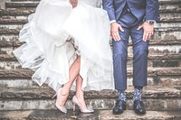 A married couple shows off their wedding dress and suit on steps. Original public domain image from Wikimedia Commons