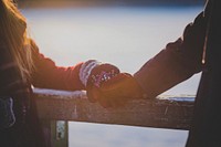 On a winter's day, young lovers hands touch on a cabin railing. Original public domain image from Wikimedia Commons