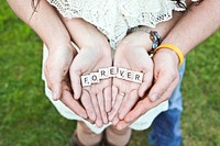 A couple's hands hold up Scrabble letters spelling out "FOREVER". Original public domain image from Wikimedia Commons