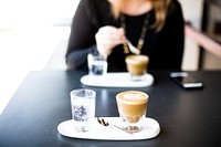 A woman sitting over a cup of coffee with another cup of coffee on the other side of the table. Original public domain image from Wikimedia Commons