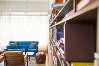 A long bookcase in a room with a sofa, a chair and a pouffe. Original public domain image from Wikimedia Commons