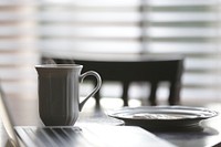 White ceramic mug beside plate on table. Original public domain image from Wikimedia Commons