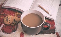 A cup of coffee in a brown mug next to some chocolate chip cookies and a book on a table. Original public domain image from Wikimedia Commons