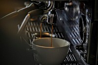 Espresso dripping into a porcelain mug from a steel machine. Original public domain image from Wikimedia Commons