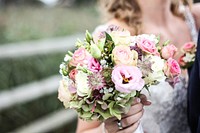 A bride holding a bouquet with pink roses and other delicate flowers. Original public domain image from Wikimedia Commons