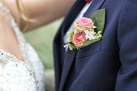 A small bouquet of roses and tiny white flowers in the buttonhole of a groom's suit. Original public domain image from Wikimedia Commons