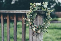 A flower crown hanging from a wooden balustrade. Original public domain image from <a href="https://commons.wikimedia.org/wiki/File:Floral_wreath_(Unsplash).jpg" target="_blank" rel="noopener noreferrer nofollow">Wikimedia Commons</a>