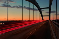 A blurry shot taken at sunrise, featuring a traffic light trail on a bridge in Djuröbron. Original public domain image from Wikimedia Commons