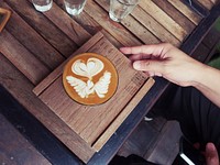 Angel wings and a heart formed the art of a cup of latte served on wood.. Original public domain image from <a href="https://commons.wikimedia.org/wiki/File:Latte_Art_Chiang_Mai_(Unsplash).jpg" target="_blank" rel="noopener noreferrer nofollow">Wikimedia Commons</a>