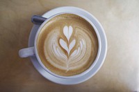 A cup of coffee with a leaf painted in the milk at Two Hands Cafe. Original public domain image from Wikimedia Commons