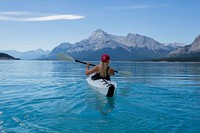 Woman wearing red hat riding on white kayak facing mountain alps. Original public domain image from <a href="https://commons.wikimedia.org/wiki/File:Nordegg,_Canada_(Unsplash_NrN5Rvl89Lo).jpg" target="_blank">Wikimedia Commons</a>