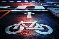 Macro of white bike lane markings on a street at night near a crosswalk. Original public domain image from Wikimedia Commons