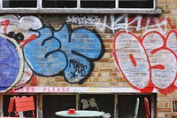 Grunge graffiti on brick wall behind colorful tables and chairs in Shoreditch. Original public domain image from <a href="https://commons.wikimedia.org/wiki/File:Coffee_time_(Unsplash).jpg" target="_blank" rel="noopener noreferrer nofollow">Wikimedia Commons</a>