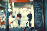 A menu is written on a chalkboard hanging outside of a cafe on the street. Original public domain image from <a href="https://commons.wikimedia.org/wiki/File:Cafe_menu_(Unsplash).jpg" target="_blank" rel="noopener noreferrer nofollow">Wikimedia Commons</a>
