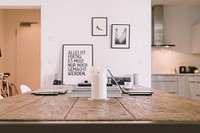 Apartment interior with wooden table and framed artwork on white wall with white candle on table. Original public domain image from <a href="https://commons.wikimedia.org/wiki/File:Wood_table_in_front_of_white_wall_(Unsplash).jpg" target="_blank" rel="noopener noreferrer nofollow">Wikimedia Commons</a>