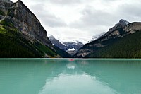 A red boat on the turquoise surface of Lake Louise surrounded by jagged mountains. Original public domain image from Wikimedia Commons