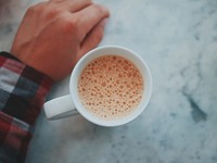 An overhead shot of a cup of coffee next to a person's hand. Original public domain image from Wikimedia Commons