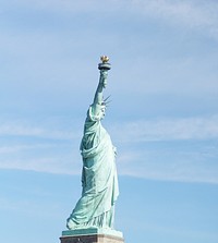 The Statue of Liberty stands tall against a bright blue sky in New York City. Original public domain image from Wikimedia Commons