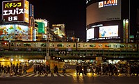 Pedestrians walk as a train tram passes overhead in Shinjuku. Original public domain image from Wikimedia Commons