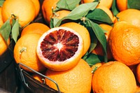 Basket of blood oranges and leaves with one cut in half. Original public domain image from Wikimedia Commons