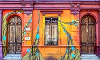 Colorful sunburst wall art on building wall with windows and wooden doors, Santiago. Original public domain image from <a href="https://commons.wikimedia.org/wiki/File:Facade_(Unsplash).jpg" target="_blank" rel="noopener noreferrer nofollow">Wikimedia Commons</a>