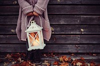 A child holding a lantern with a candle near a wooden wall in the autumn. Original public domain image from <a href="https://commons.wikimedia.org/wiki/File:Child_with_a_lantern_(Unsplash).jpg" target="_blank" rel="noopener noreferrer nofollow">Wikimedia Commons</a>