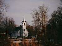 A small white church surrounded by trees. Original public domain image from Wikimedia Commons