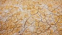 Aerial drone shot of cracks in yellow and white sandy desert floor. Original public domain image from <a href="https://commons.wikimedia.org/wiki/File:Cracked_Earth_(Unsplash).jpg" target="_blank" rel="noopener noreferrer nofollow">Wikimedia Commons</a>