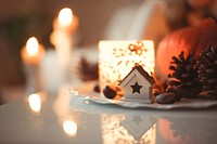 A macro view of a festive Christmas ornament on a table with candles blurrily lit in the background.. Original public domain image from Wikimedia Commons